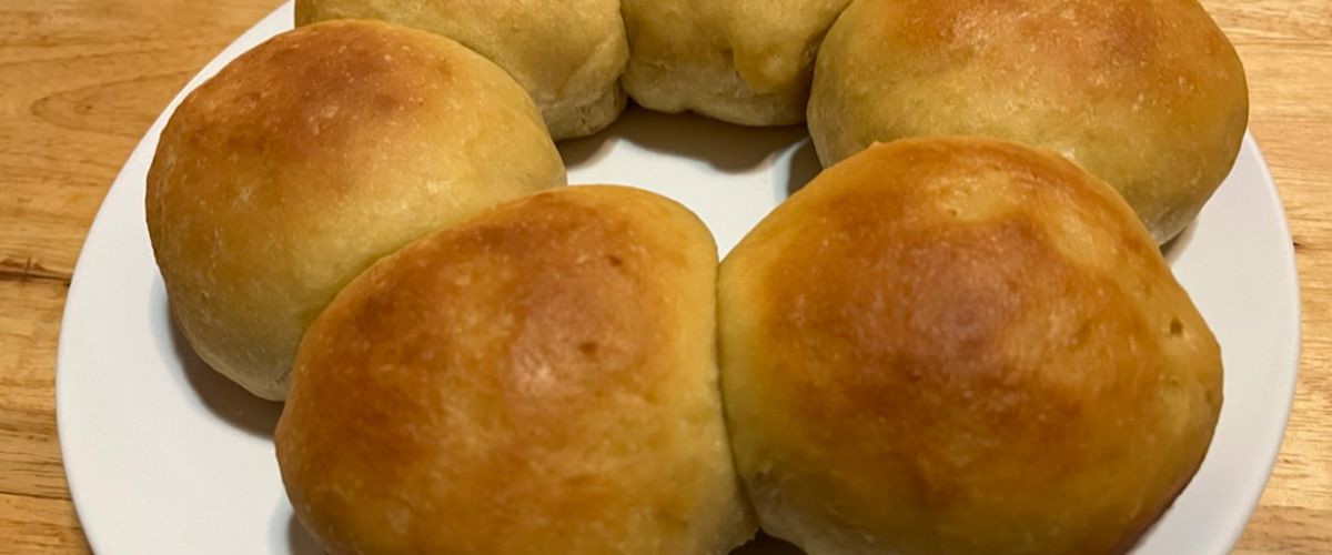 6 golden brown rolls on a white plate