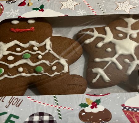 Gingerbread people and stars in gift box with gingerbread people and cupcakes on it