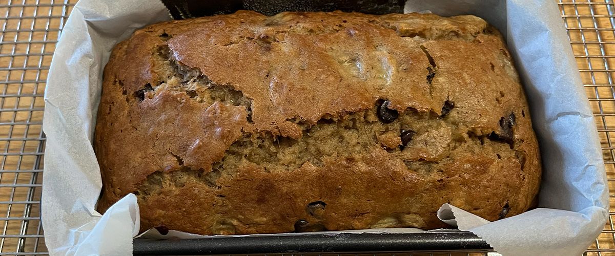 Close up of banana bread in a loaf pan with parchment paper