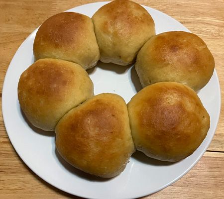 6 golden brown rolls on a white plate