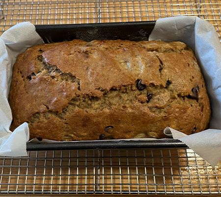 Close up of banana bread in a loaf pan with parchment paper